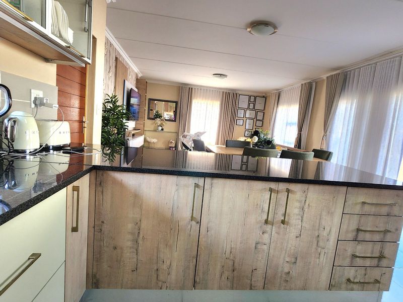 Spacious open-plan kitchen and living area featuring modern wood-look cabinetry, granite countertops, and large windows providing ample natural light.