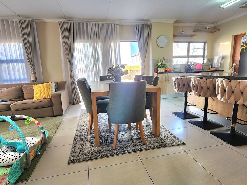Spacious open-plan living and dining area featuring tiled floors, modern kitchen cabinetry with a breakfast island, and large sliding doors leading to the exterior.