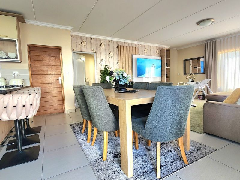 Spacious open-plan living and dining area featuring a modern kitchen with granite countertops, tiled flooring, and stylish feature wall paneling.