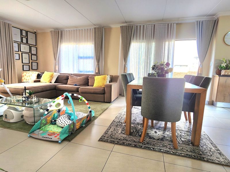 Spacious open-plan living and dining area featuring large sliding glass doors, neutral tiled flooring, and an integrated kitchen space.
