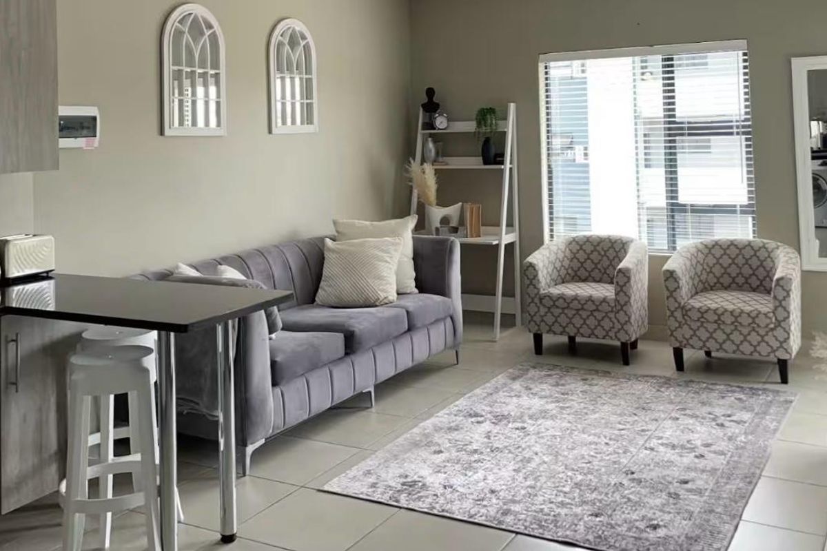A well-maintained open-plan living area featuring tiled flooring, a modern breakfast bar, and integrated kitchen cabinetry with neutral wall finishes.