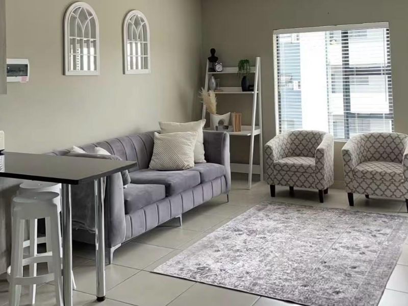 A well-maintained open-plan living area featuring tiled flooring, a modern breakfast bar, and integrated kitchen cabinetry with neutral wall finishes.