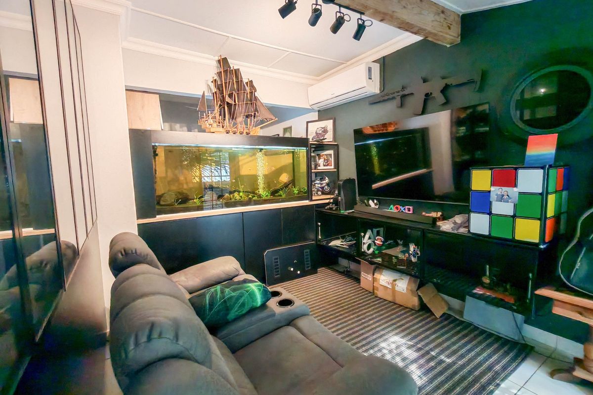 A living room featuring tiled flooring, track lighting, an exposed timber beam, and built-in cabinetry with an integrated air conditioning unit.