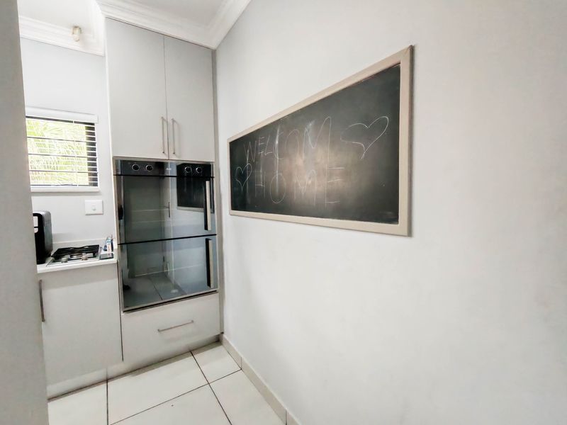 Modern kitchen area featuring built-in double oven, gas hob, and clean tiled flooring with neutral cabinetry.