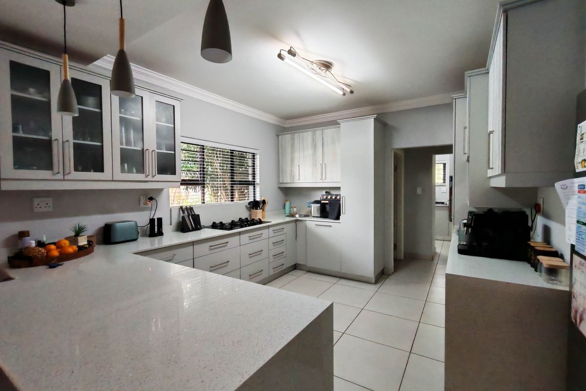 Modern kitchen featuring light-toned cabinetry, quartz countertops, a gas hob, and tiled flooring, offering a clean and functional workspace.