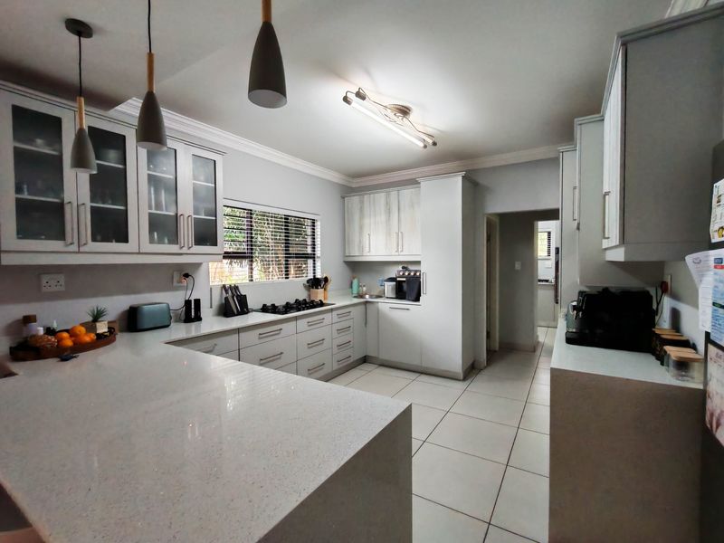 Modern kitchen featuring light-toned cabinetry, quartz countertops, a gas hob, and tiled flooring, offering a clean and functional workspace.