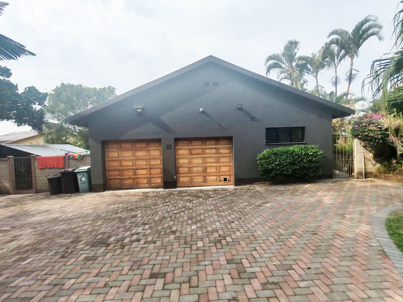 Front view of a residential property featuring a double garage with timber doors and a paved driveway.