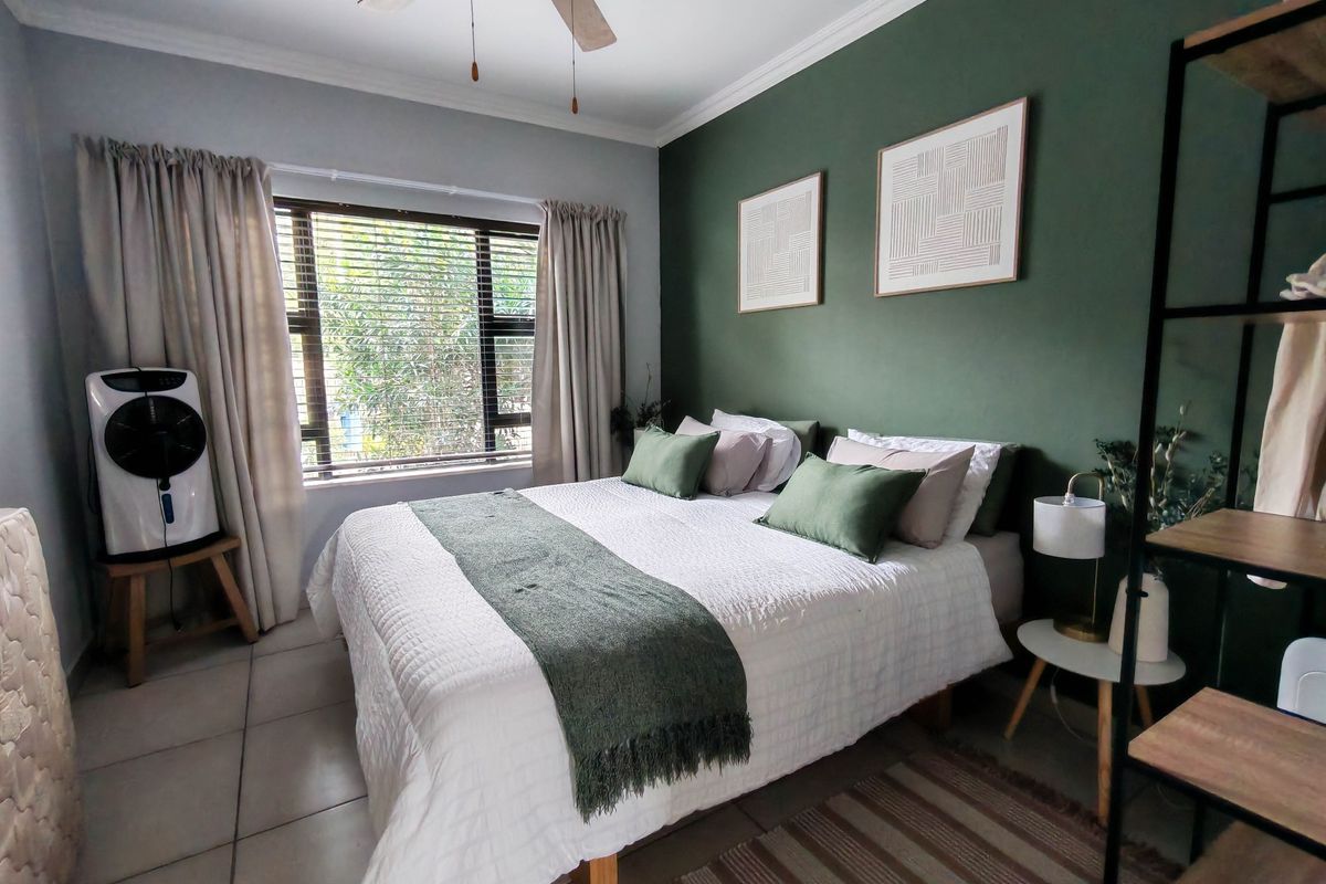 A well-maintained bedroom featuring tiled flooring, a ceiling fan, and a large window with natural light.