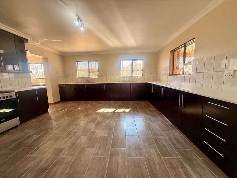 Spacious kitchen featuring dark wood cabinetry, tiled backsplash, and ceramic flooring, offering a clean and functional layout ready for personalization.