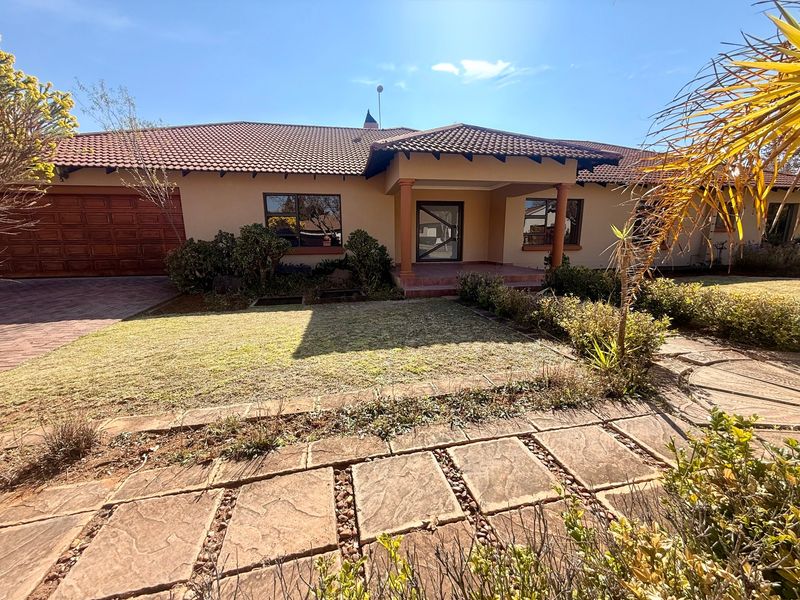 Front elevation of a single-story house featuring a tiled roof, double garage, covered entrance porch, and a paved front garden area.