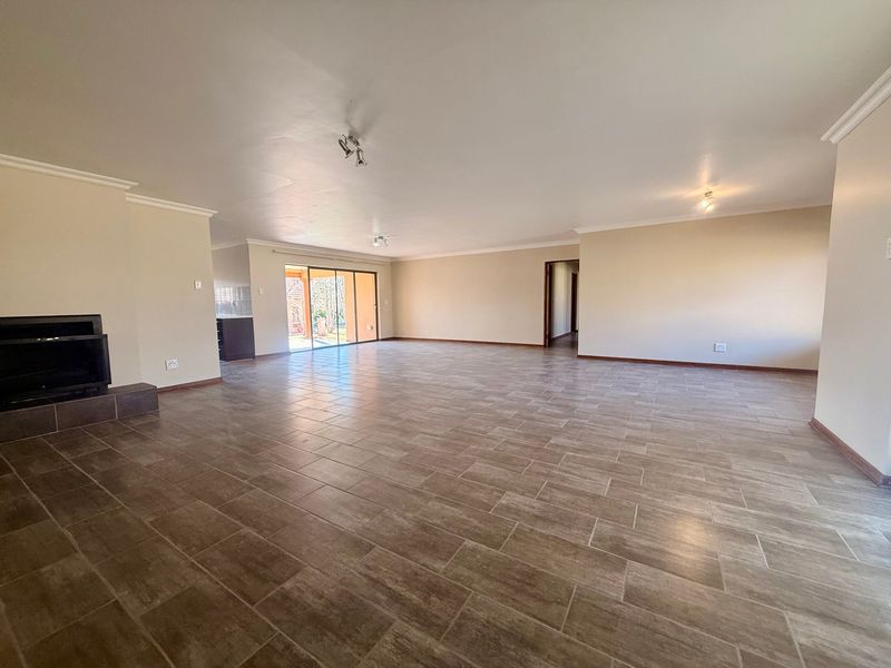 Spacious open-plan living area featuring neutral tiled flooring, a built-in fireplace, and sliding glass doors leading to the exterior.