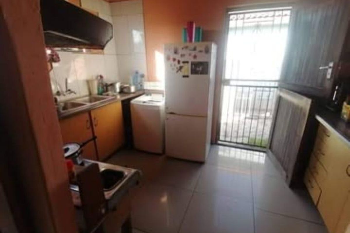 A functional kitchen featuring built-in cabinetry, a double sink, and an extractor fan, with direct access to an exterior security gate.