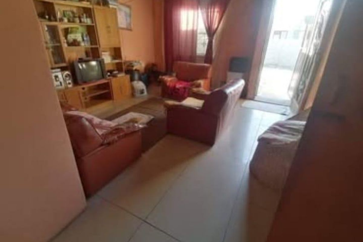 A living room area featuring tiled flooring and a glass sliding door leading to an outdoor space.
