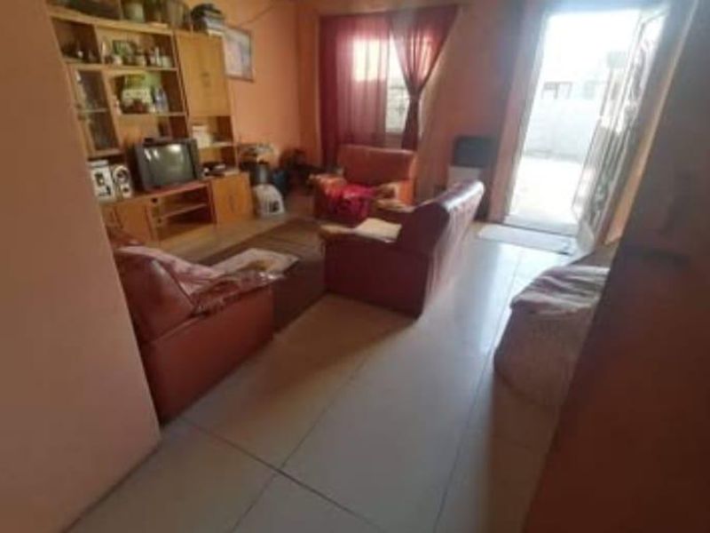 A living room area featuring tiled flooring and a glass sliding door leading to an outdoor space.