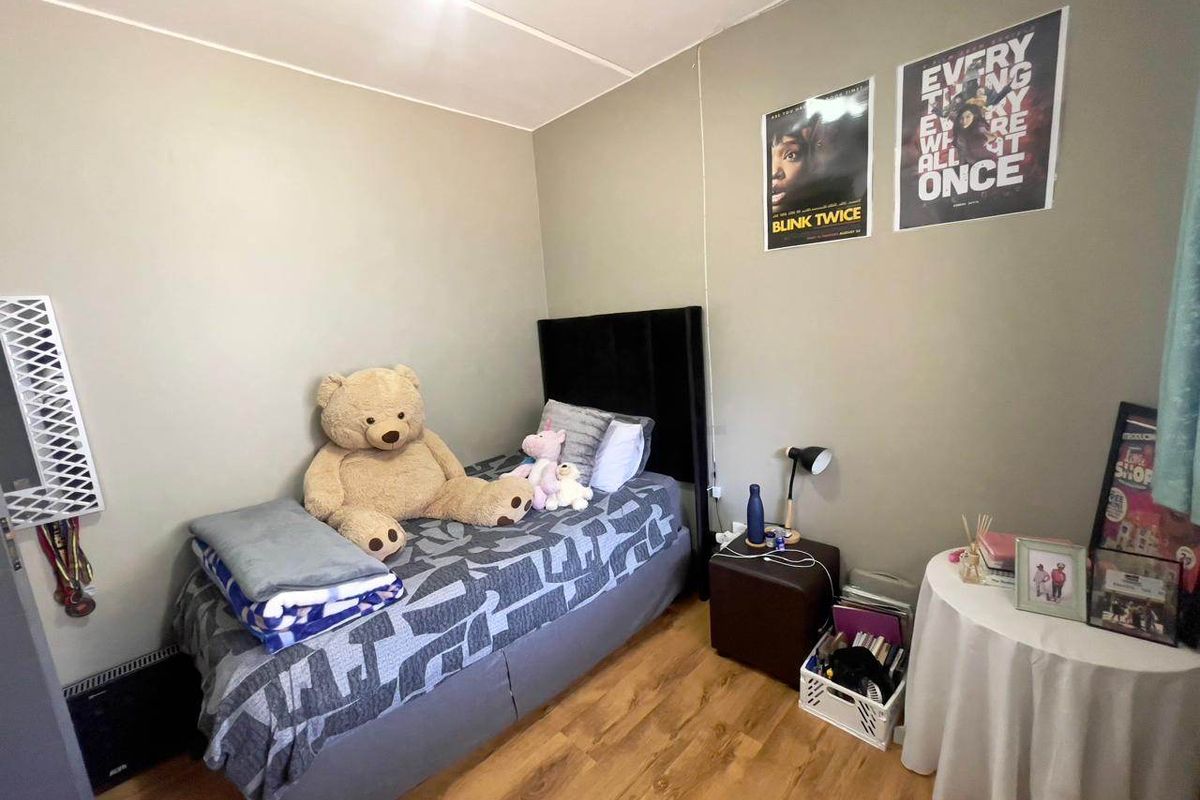 A functional bedroom featuring laminate flooring and a wall-mounted heater, offering a neutral base for personalization.