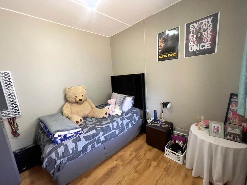 A functional bedroom featuring laminate flooring and a wall-mounted heater, offering a neutral base for personalization.