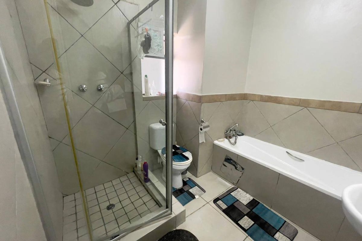 A functional bathroom featuring a separate shower enclosure, bathtub, and toilet with neutral wall and floor tiling.