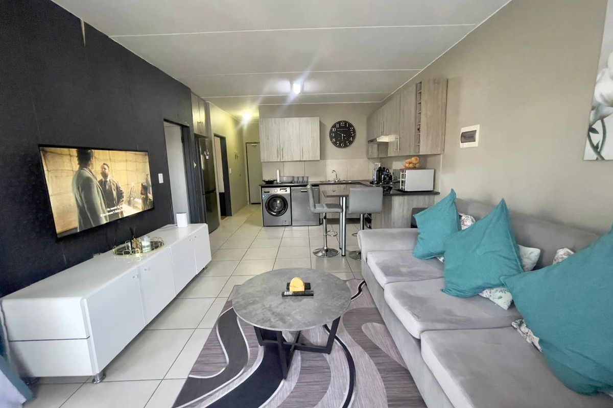 Open-plan living area featuring a compact kitchen with built-in cabinetry, tiled flooring, and a combined lounge space.