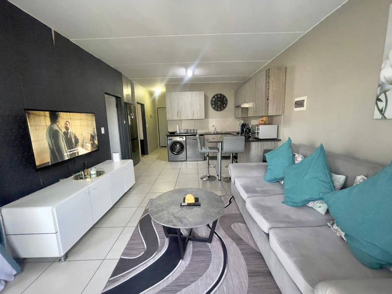 Open-plan living area featuring a compact kitchen with built-in cabinetry, tiled flooring, and a combined lounge space.