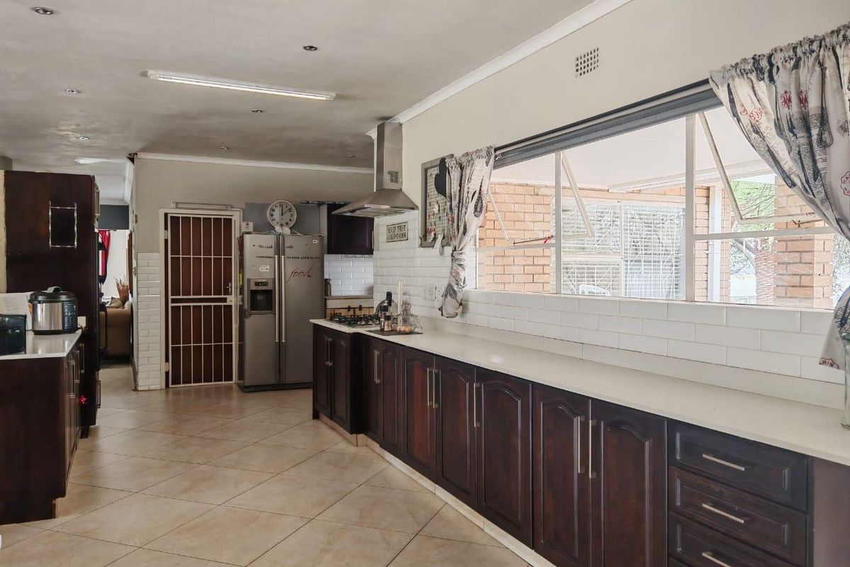Spacious kitchen featuring dark wood cabinetry, stone countertops, subway tile backsplash, and a gas hob with stainless steel extractor fan.