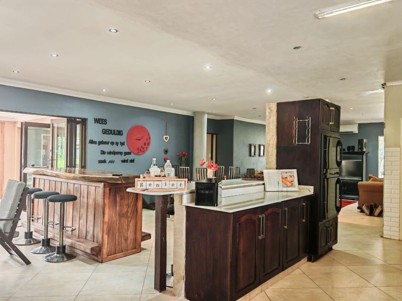 Spacious open-plan living area featuring a built-in bar, kitchen cabinetry with stone countertops, and tiled flooring throughout.