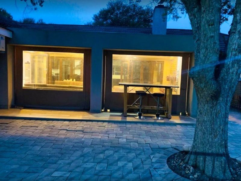 A covered outdoor patio area featuring paved flooring, external blinds, and a chimney, providing a functional space for outdoor living.