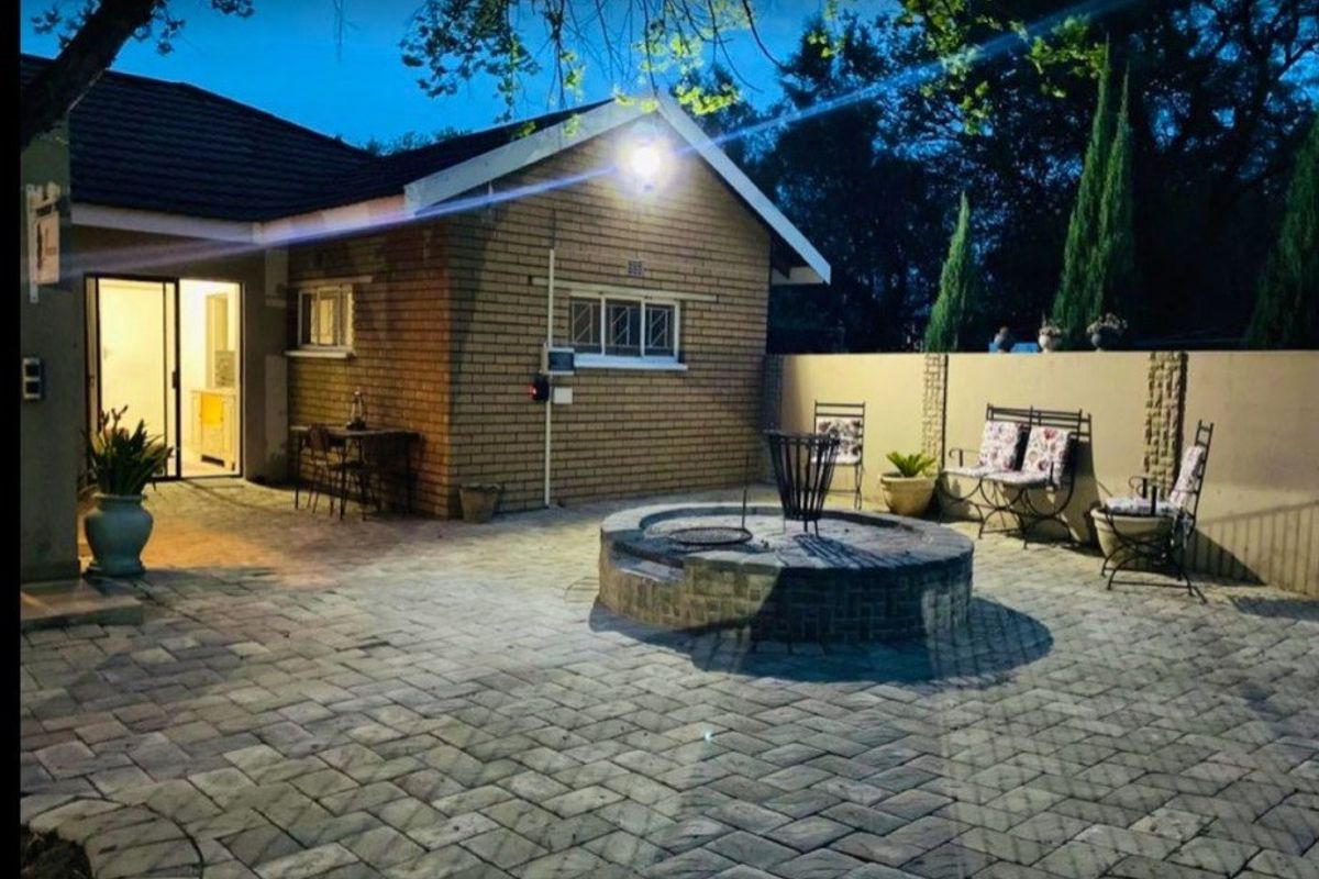 Rear exterior view featuring a paved patio area with a built-in brick fire pit and access to the home via a sliding glass door.