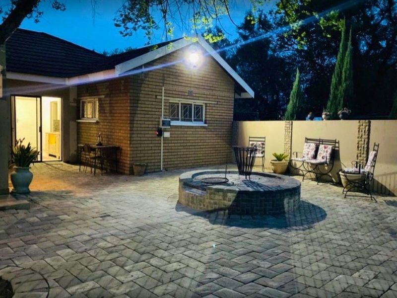 Rear exterior view featuring a paved patio area with a built-in brick fire pit and access to the home via a sliding glass door.