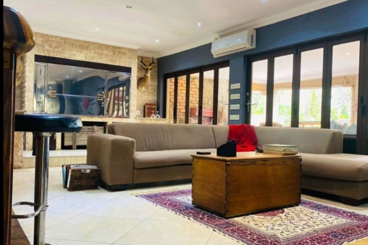 Spacious living room featuring tiled flooring, a stone feature wall with a built-in fireplace, and bi-fold doors opening to the outdoor area.