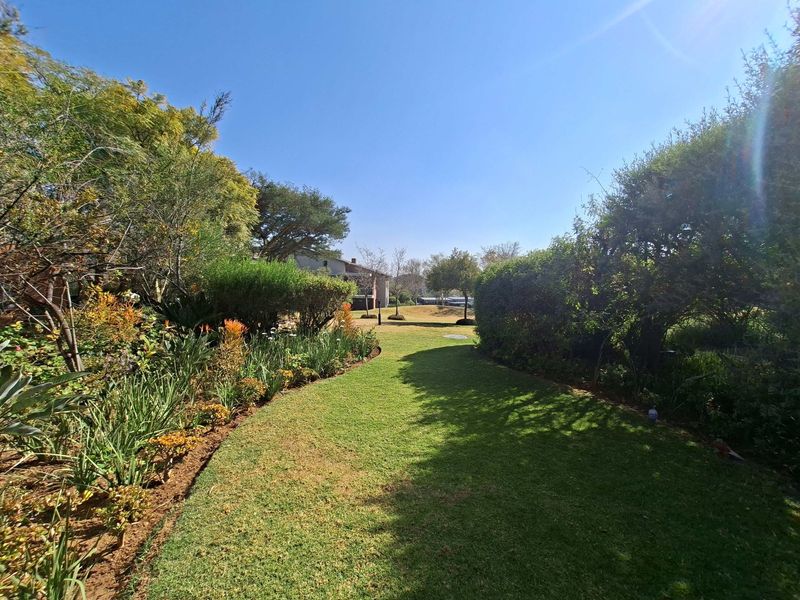 A well-maintained private garden featuring a lush green lawn, established flower beds, and mature landscaping.