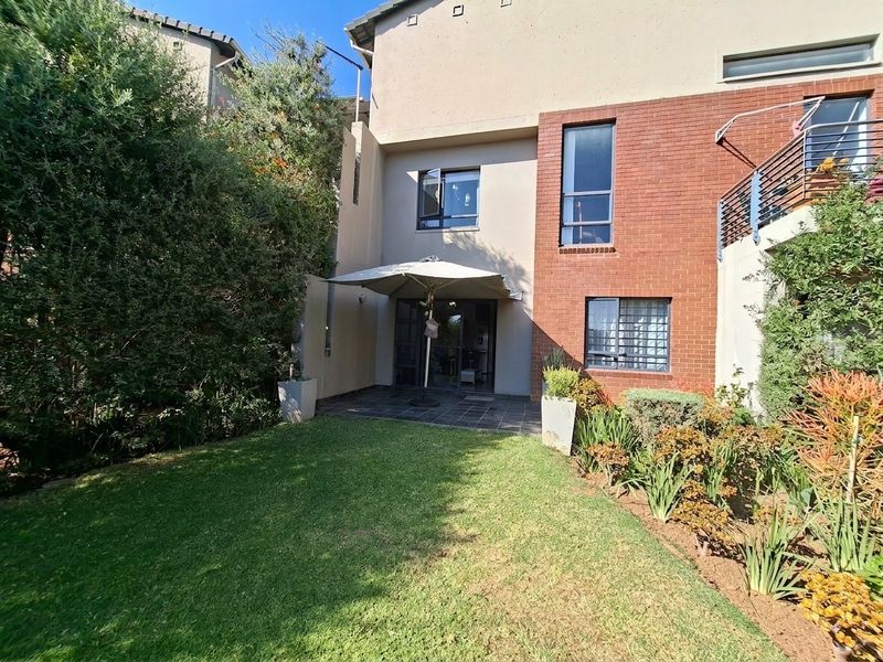 Rear view of the apartment featuring a private garden, tiled patio area, and a combination of brick and rendered exterior finishes.