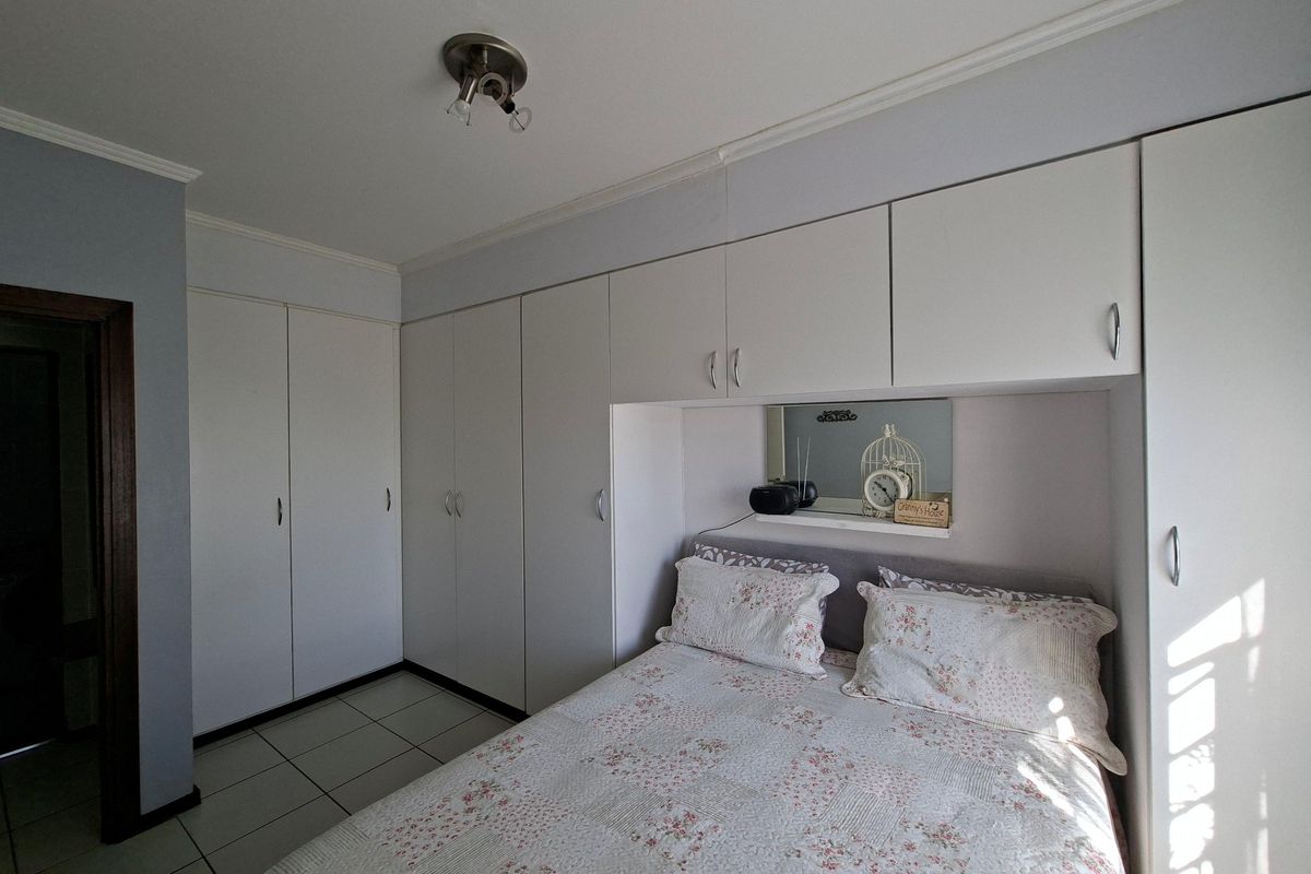 A bedroom featuring extensive white built-in cupboards with integrated shelving and tiled flooring.