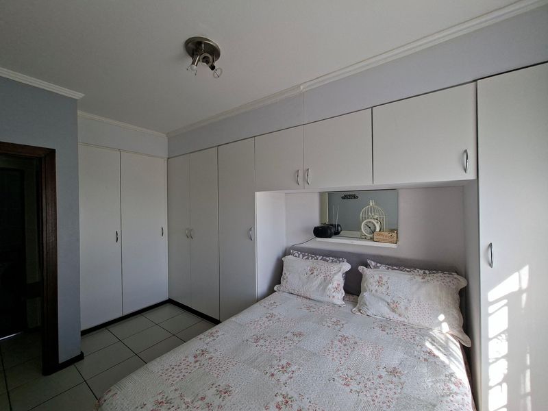 A bedroom featuring extensive white built-in cupboards with integrated shelving and tiled flooring.