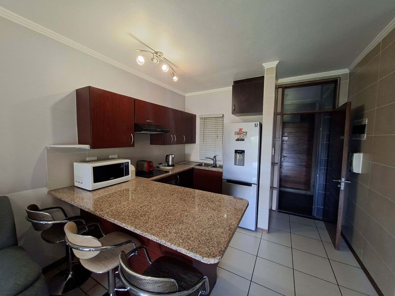 Compact kitchen featuring granite countertops, built-in cabinetry, a breakfast bar, and tiled flooring, providing a functional space for cooking and dining.