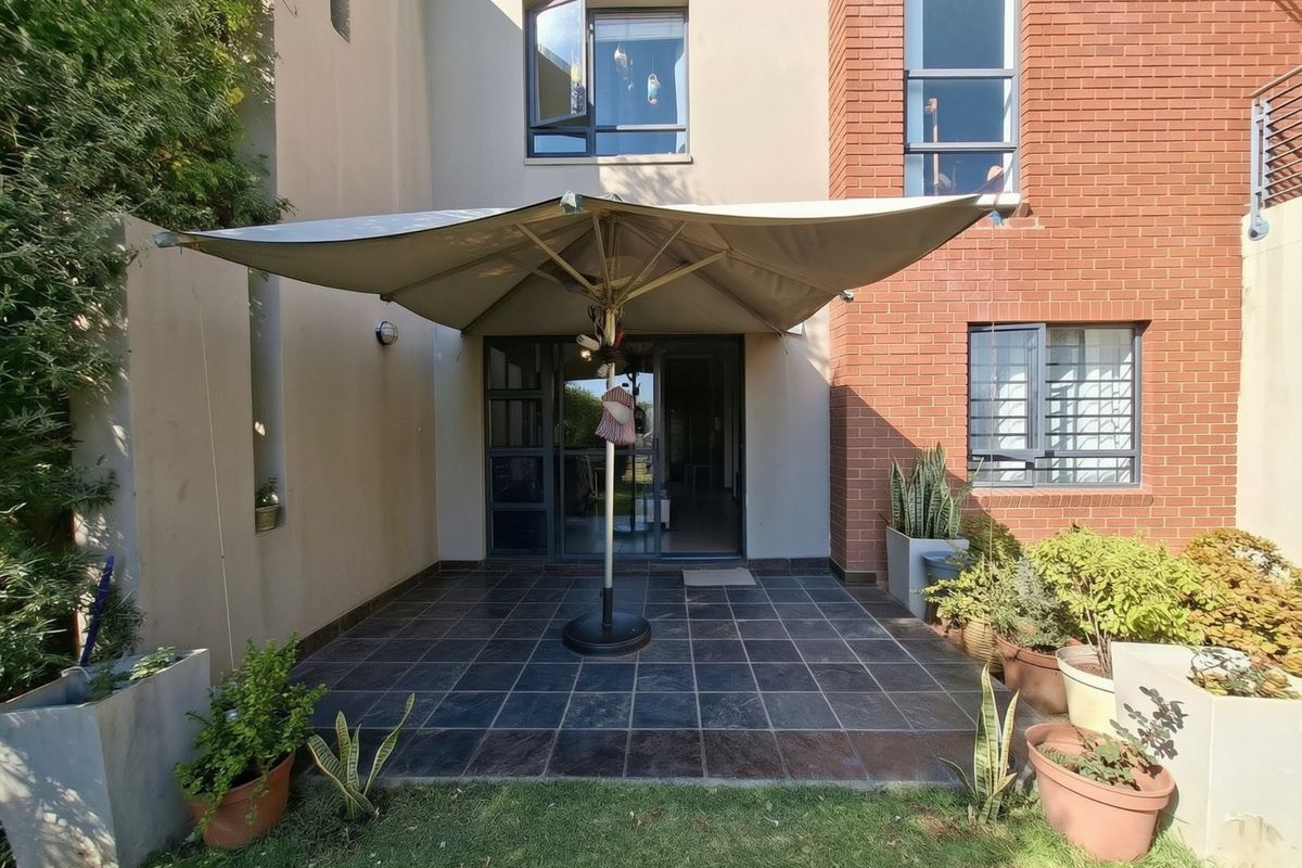 A rear patio area featuring dark floor tiles, brick and rendered wall finishes, and access to the interior via a sliding glass door.
