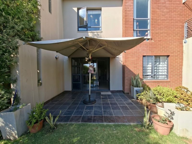 A rear patio area featuring dark floor tiles, brick and rendered wall finishes, and access to the interior via a sliding glass door.