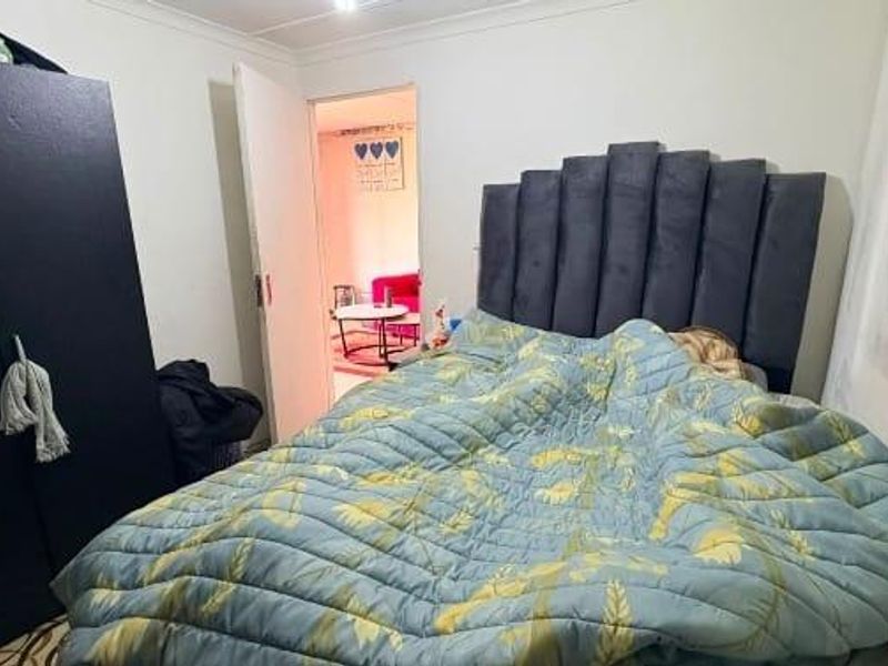 A compact bedroom featuring a built-in wardrobe and coving, currently showing signs of wear on the wall surfaces.