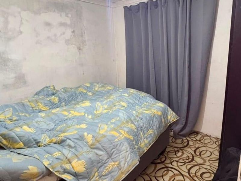A bedroom featuring patterned flooring and visible signs of wall and ceiling deterioration requiring maintenance and cosmetic updates.