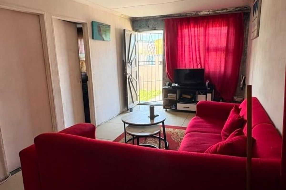 A compact living room featuring tiled flooring and direct access to an exterior area through a security gate.