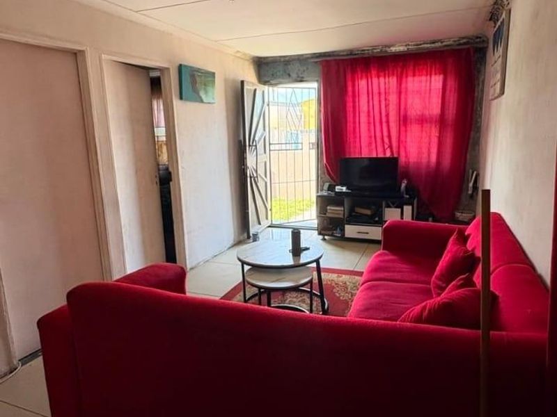 A compact living room featuring tiled flooring and direct access to an exterior area through a security gate.
