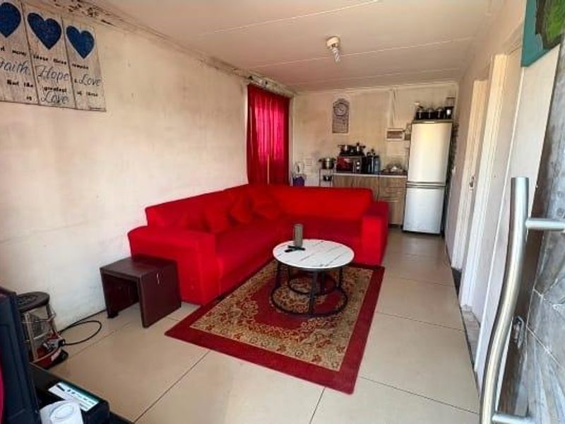 Open-plan living area featuring tiled flooring and a compact kitchen corner with built-in cabinetry.
