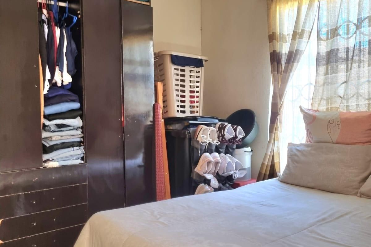 A functional bedroom featuring a built-in wardrobe and natural light from the window.