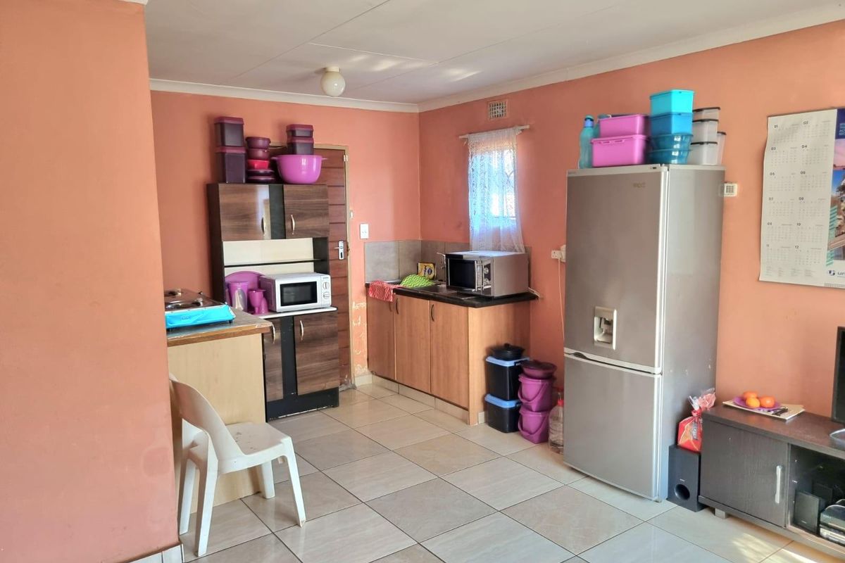 A functional kitchen area featuring tiled flooring and built-in cabinetry, offering a practical layout with space for essential appliances.