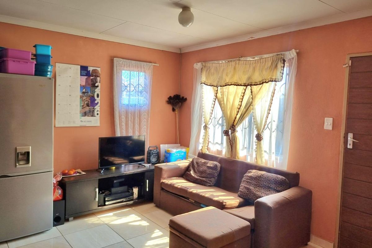 A living room featuring tiled flooring and security bars on the windows, with visible wear on the walls and ceiling.