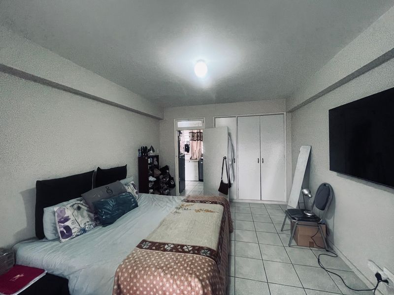 A functional bedroom featuring tiled flooring, a built-in wardrobe, and direct access to an adjacent utility area.