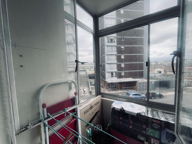 Enclosed balcony area featuring aluminium window frames and views of the surrounding apartment complex.