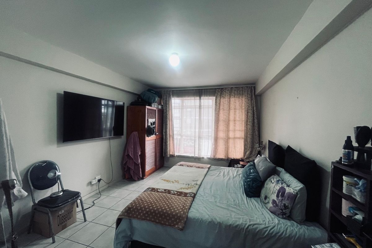 A functional bedroom featuring tiled flooring and a built-in wardrobe, offering a practical layout with natural light from the window.