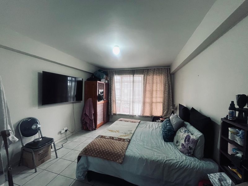 A functional bedroom featuring tiled flooring and a built-in wardrobe, offering a practical layout with natural light from the window.
