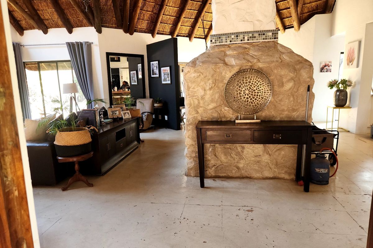 Spacious living area featuring a high vaulted thatched ceiling with exposed timber rafters and a prominent central stone fireplace.