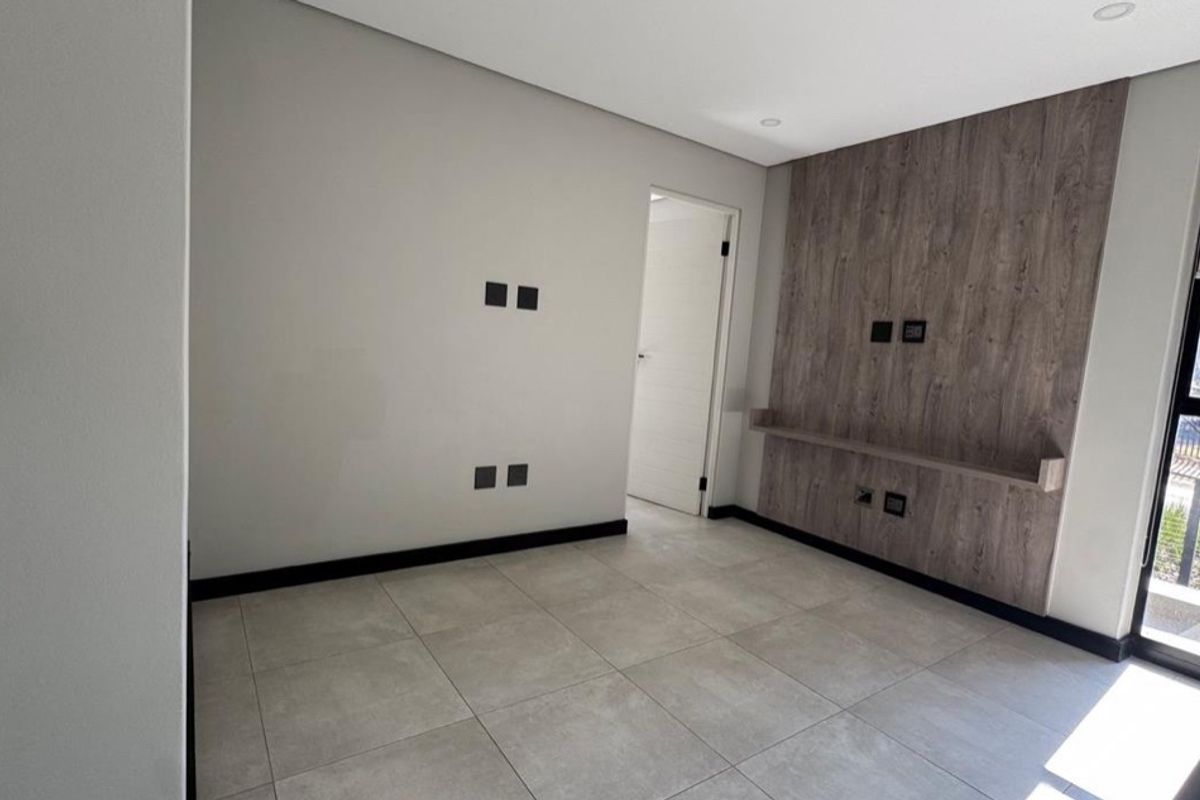Modern bedroom featuring large format floor tiles, a wood-look feature wall with a built-in shelf, and recessed lighting.